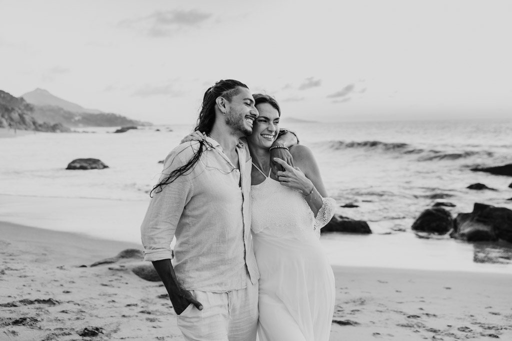 Black and white photo of happy couple laughing together on a sandy beach near the ocean during their Sayulita engagement session