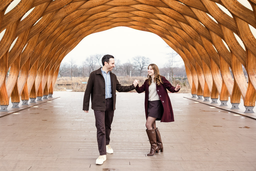 Engaged couple holds hands and dances under the Lincoln Park Honeycomb