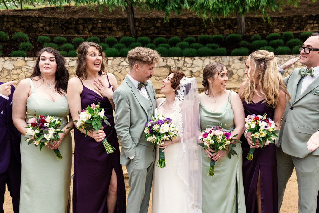 Wedding party poses outdoors at a Terra Mia Vineyard wedding, with the bride and bridesmaids holding bouquets and smiling