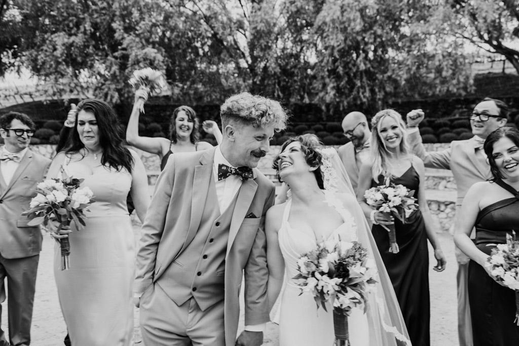 Bride and groom walk hand in hand after their Terra Mia Vineyard wedding ceremony, surrounded by laughing members of the wedding party