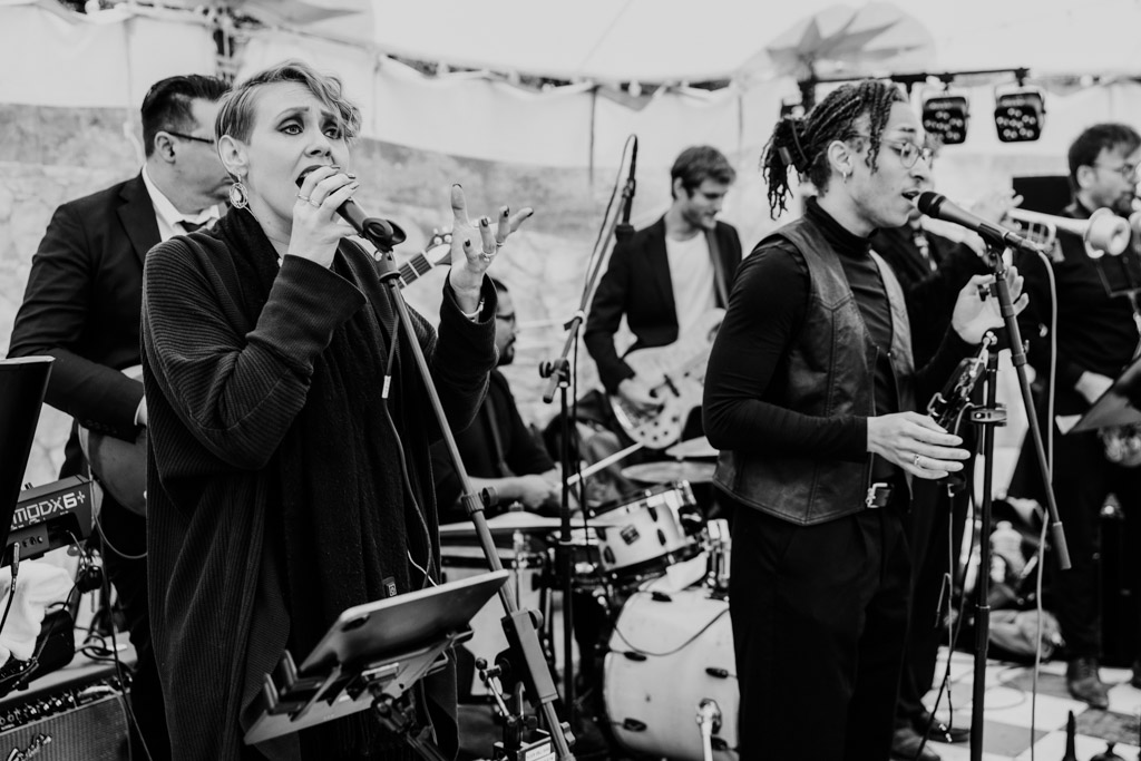 Black and white photo of band featuring guitars, drums, and horns performing during wedding reception at Terra Mia Vineyard