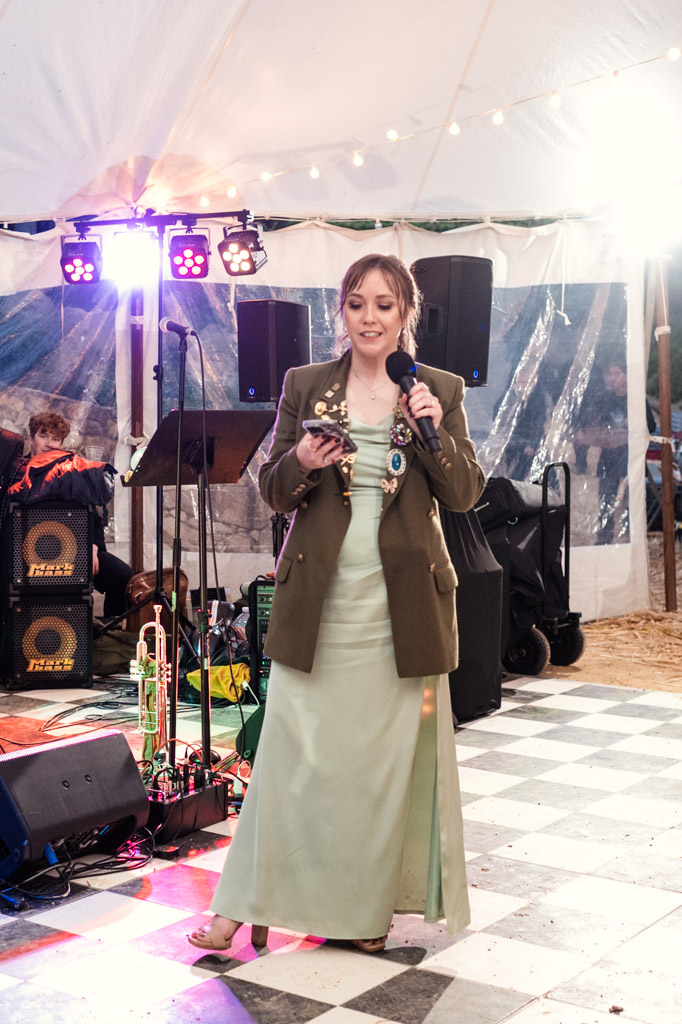 Bridesmaid in a green dress and blazer gives speech at Terra Mia Vineyard wedding reception