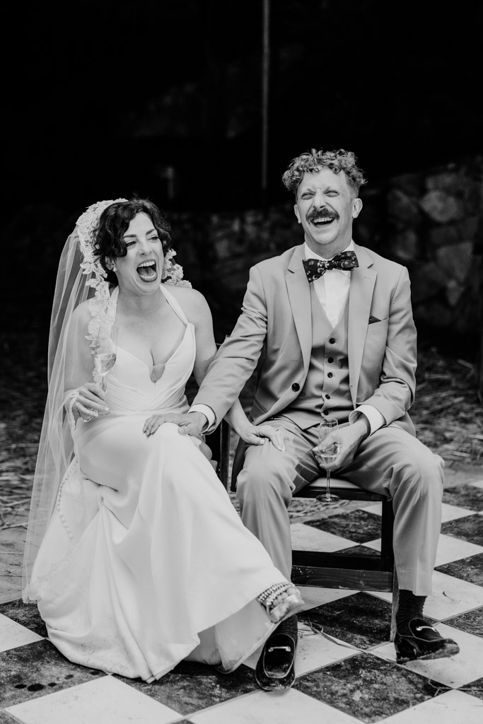 Black and white photo of newlyweds laughing during speech at their Terra Mia Vineyard wedding reception