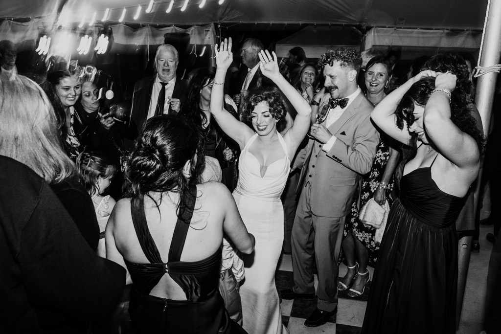Black and white photo of bride and groom dancing with guests at their Terra Mia Vineyard wedding reception
