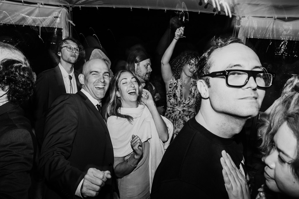Black and white photo of guests dancing together at a lively indoor party during wedding reception at Terra Mia Vineyard