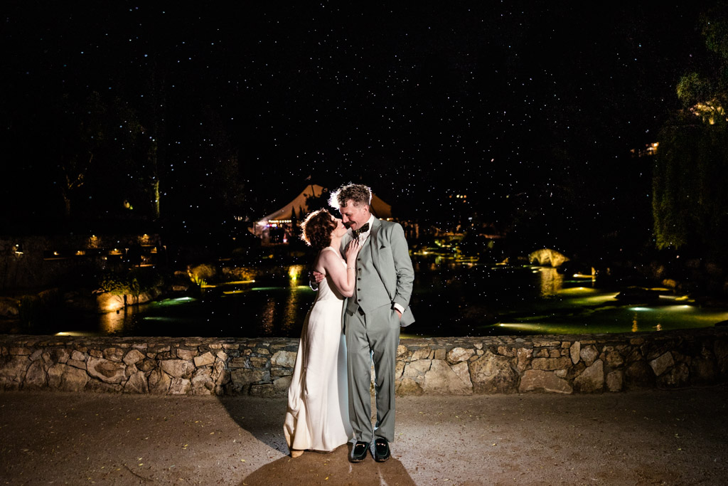 Bride and groom embrace outdoors at night in light rain during their romantic Terra Mia Vineyard wedding reception