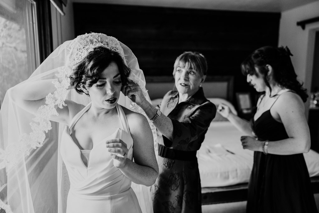Black and white photo of bride's mother helping bride adjust her veil before her wedding at Terra Mia Vineyard in Paso Robles, California