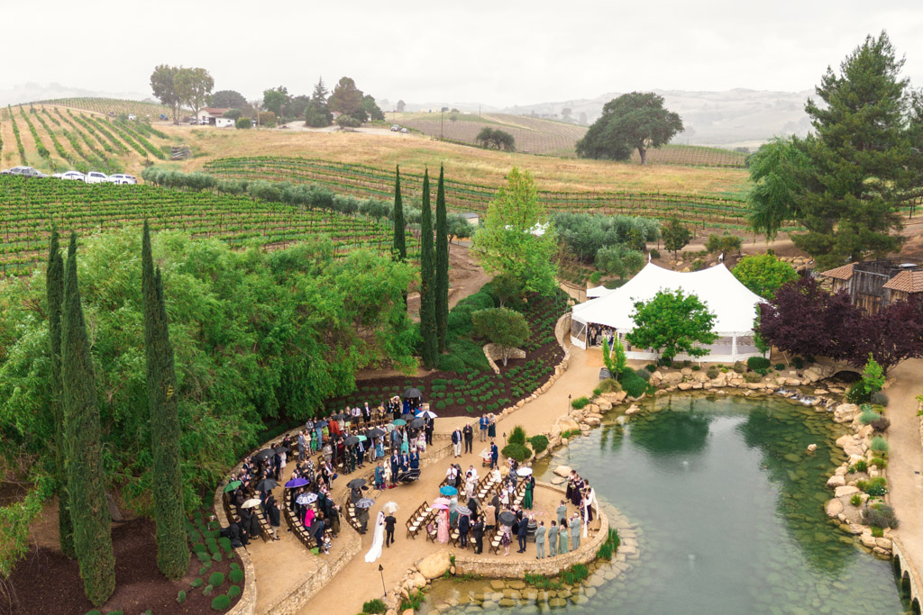 Aerial view of bride and her father walking down the aisle during her wedding ceremony at Terra Mia Vineyard in Paso Robles, California