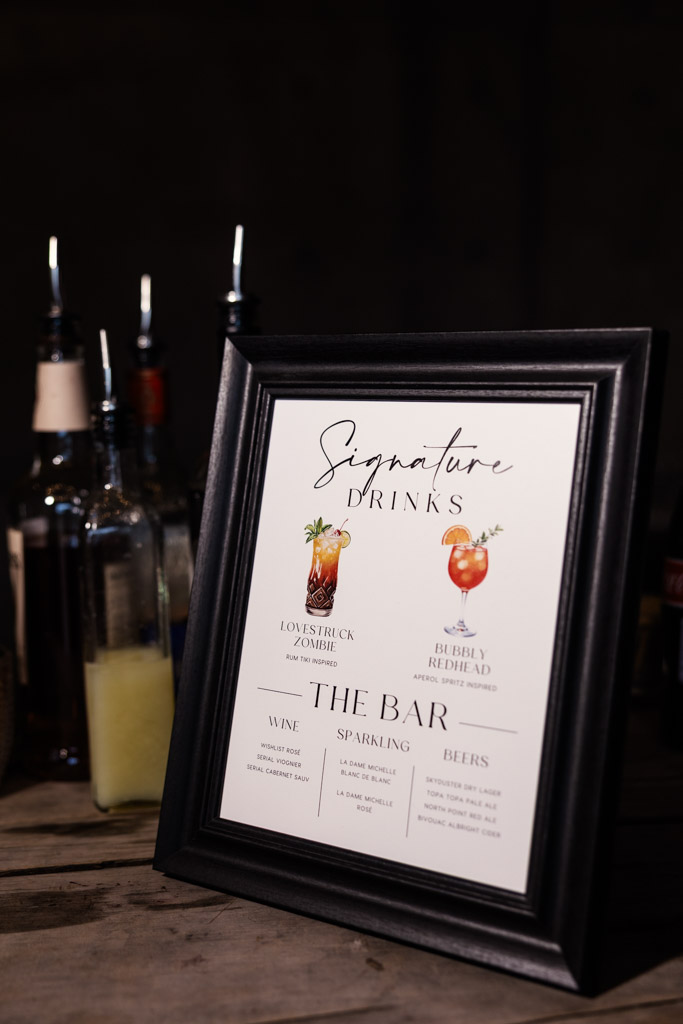 A framed signature drinks menu on a bar, surrounded by various bottles and drink mixers for wedding reception at Terra Mia Vineyard in Paso Robles, California