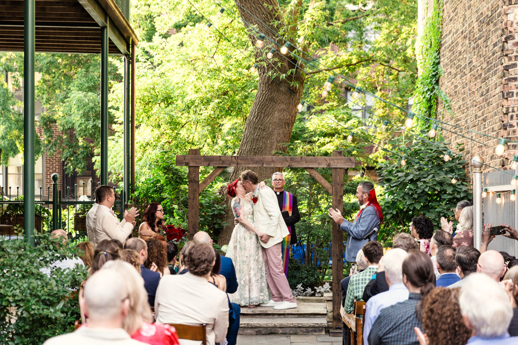 Newlywed couple kisses at their outdoor Firehouse Chicago wedding ceremony as guests watch