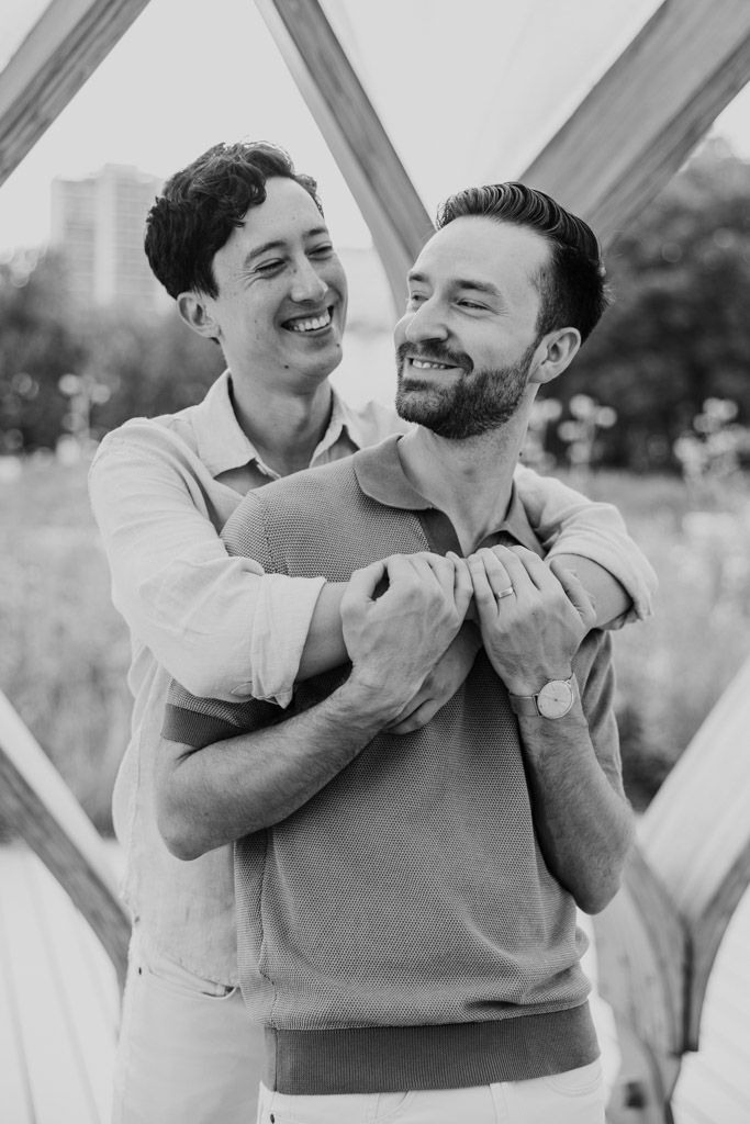 Black and white photo of engaged couple under the Honeycomb holding each other during their Lincoln Park engagement session