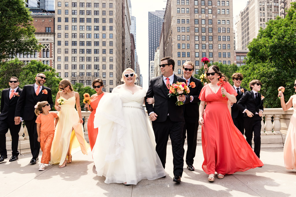 Wedding party in colorful attire walking outdoors in a city, smiling and celebrating together.