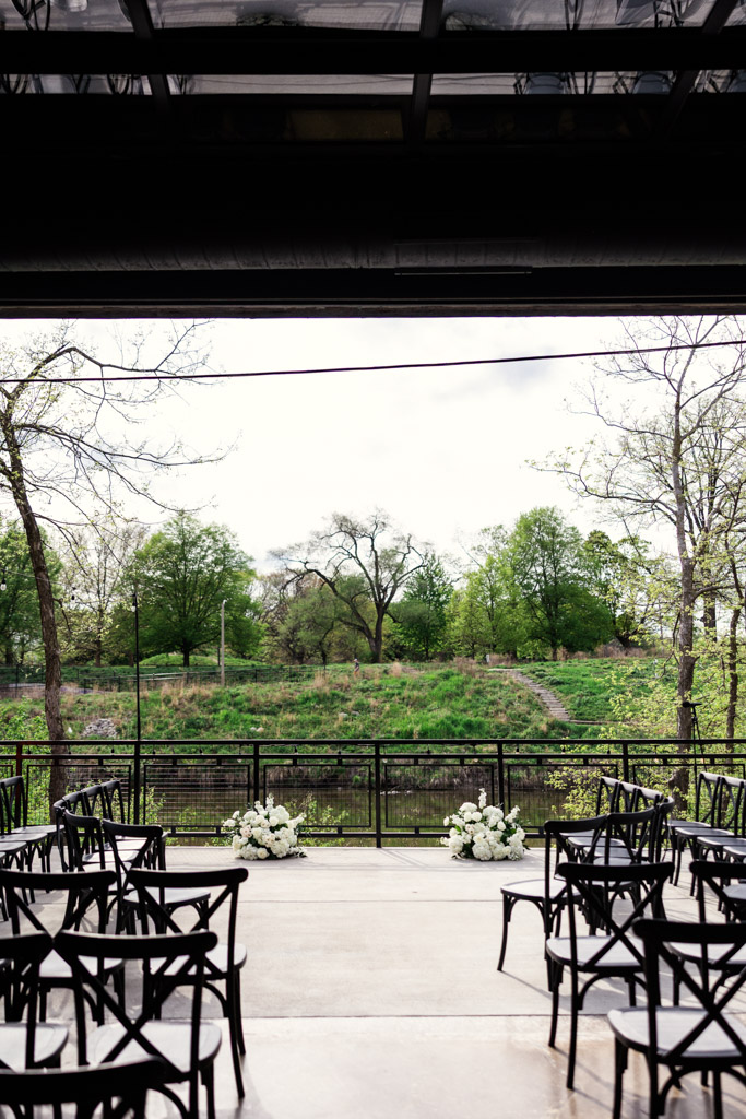 Outdoor wedding ceremony space at River Room at Burning Bush Brewery with a backdrop of the river and lush trees