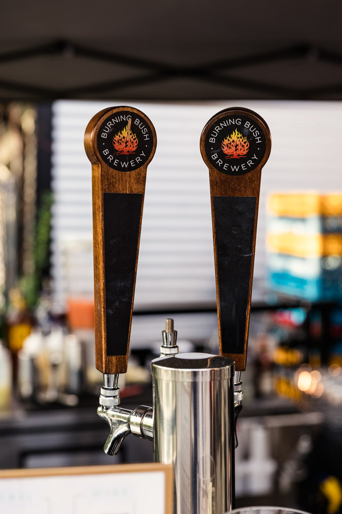 Two Burning Bush Brewery beer taps at an outdoor bar setup for River Room wedding reception