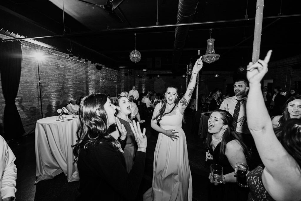 Black and white photo of bride and guests together on the dance floor during her wedding reception at River Room