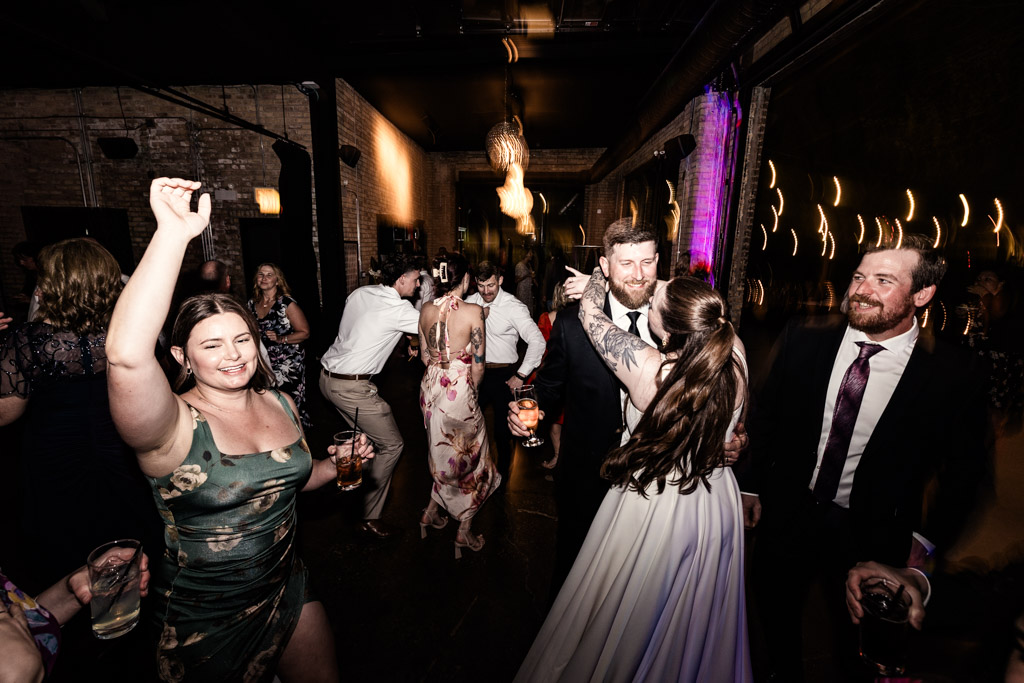 Bride, groom and guests dancing and celebrating during wedding reception at River Room