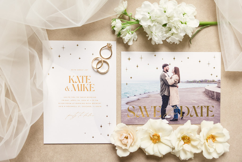 Wedding invitation, rings, flowers, and a photo of a couple by a lake for wedding celebration at River Room at Burning Bush Brewery