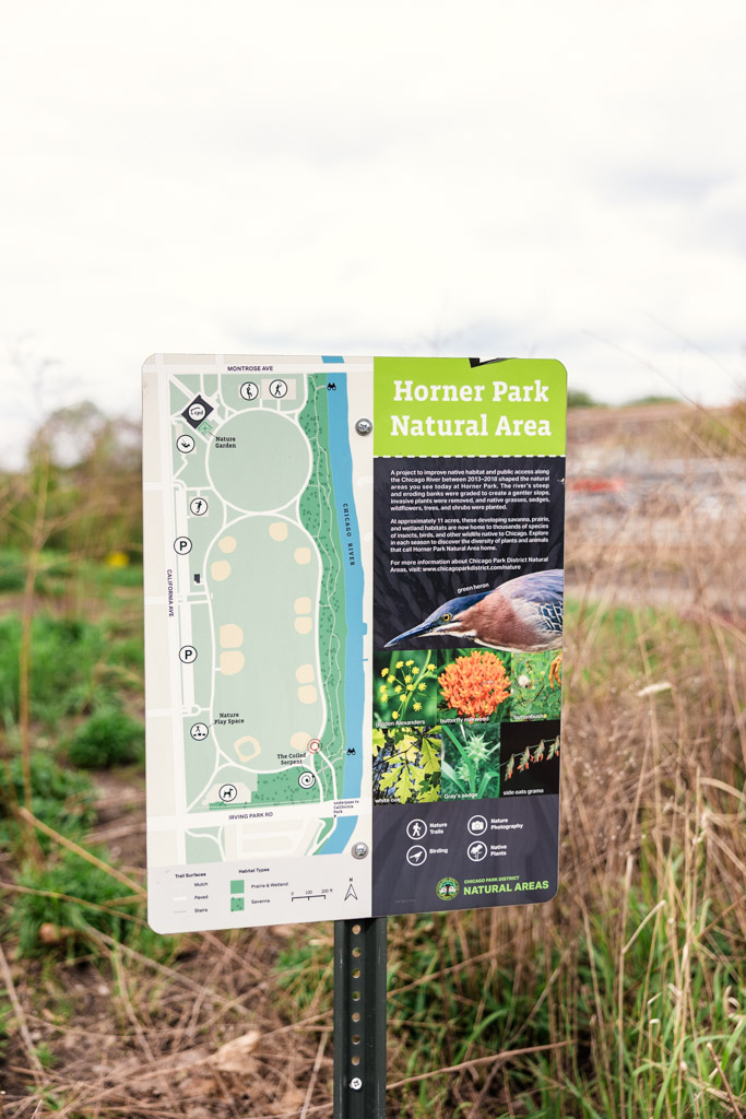 Sign for Horner Park Natural Area with a park map, park info, and a bird photo, set amid grass and plants