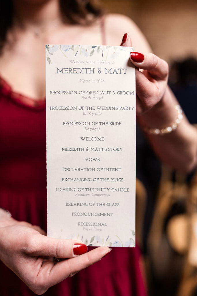 Person holding a wedding ceremony program at The Arbory, listing the order of events