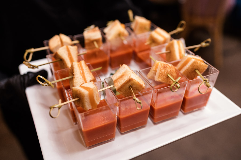 Mini grilled cheese skewers on cups of tomato soup, arranged neatly on a white tray, for wedding reception at The Arbory