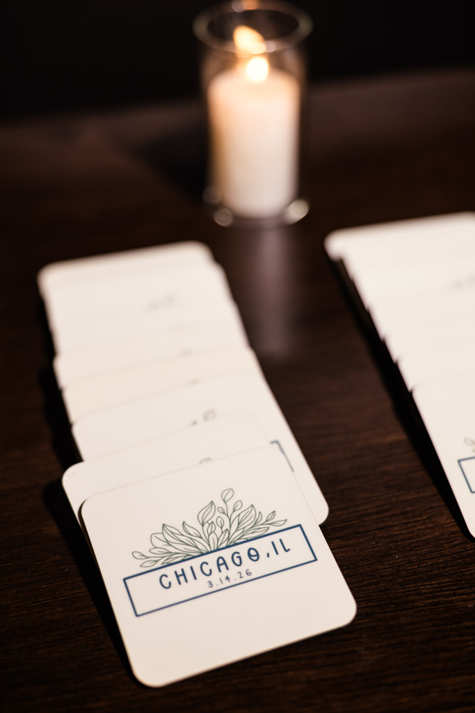 Stacked custom coasters on a table at The Arbory, with a lit candle in the background