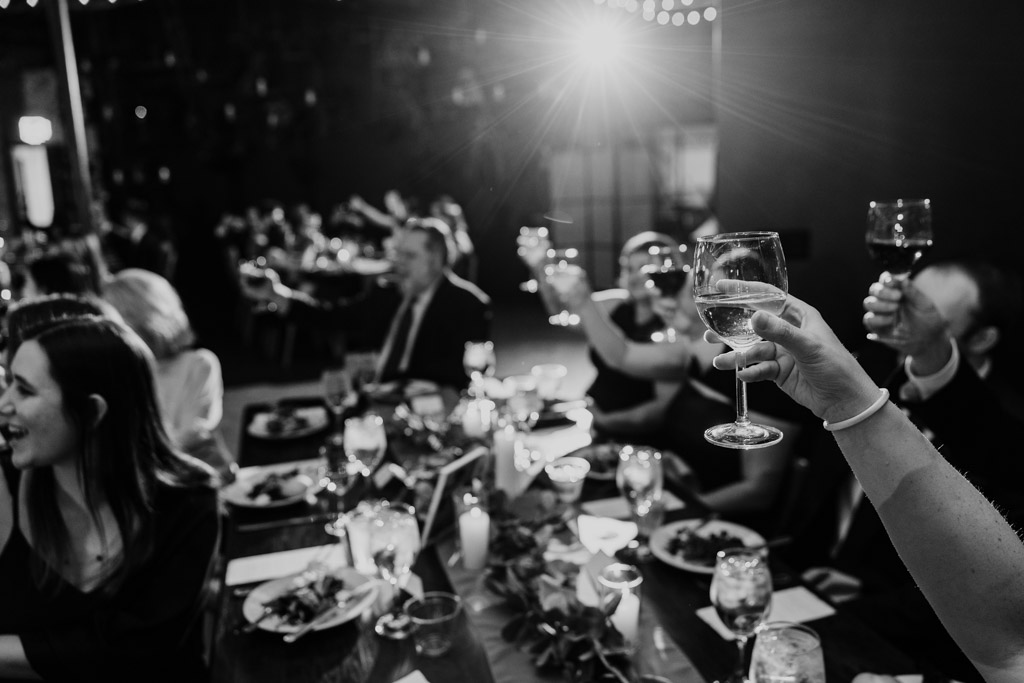 Black and white photo of guests at The Arbory raising glasses in a celebratory toast