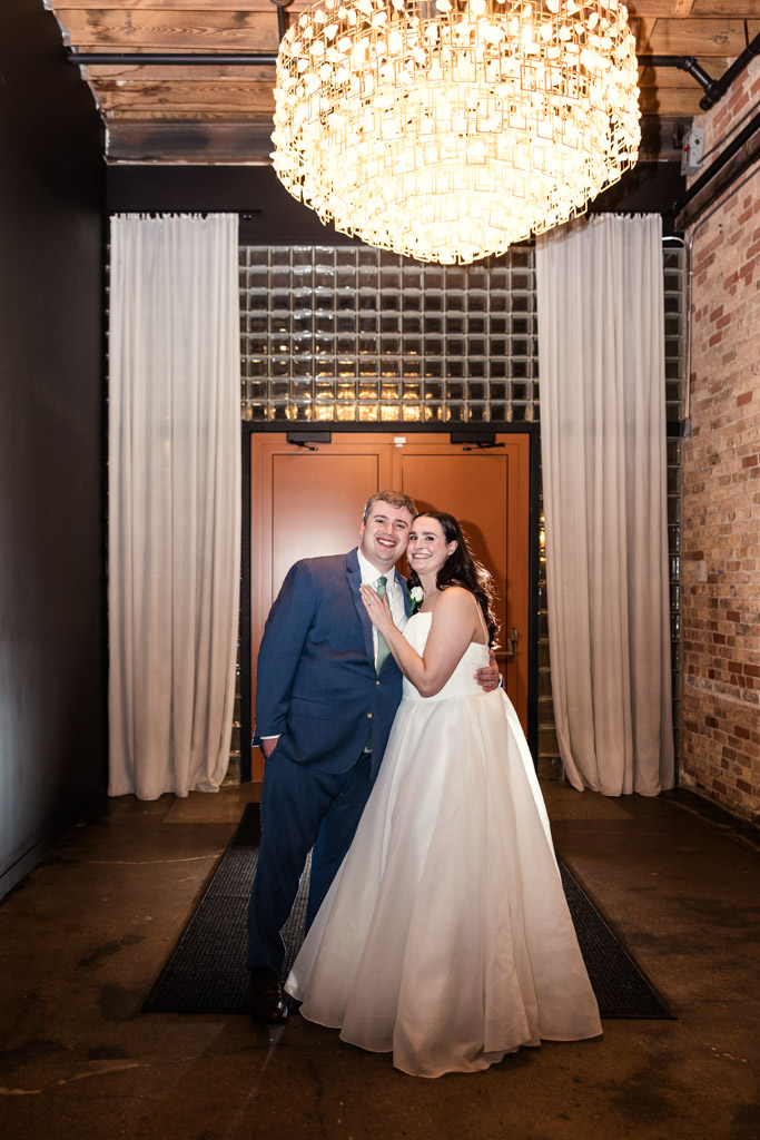 Portrait of happy newlyweds under a chandelier inside The Arbory