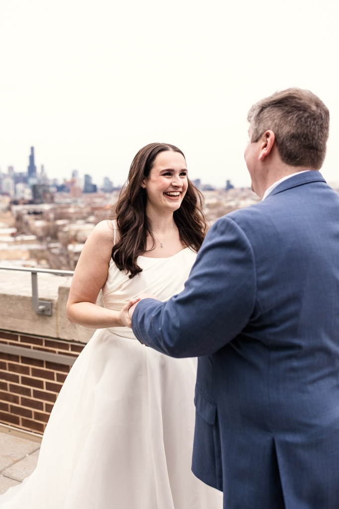 Bride and groom smile at each other on the rooftop of The Robey outside Up Room with the Chicago skyline in the background