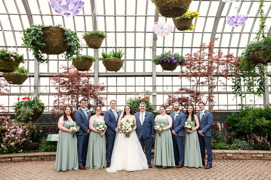 Portrait of wedding party inside the Show House at Garfield Park Conservatory with hanging plants and lush greenery in the background