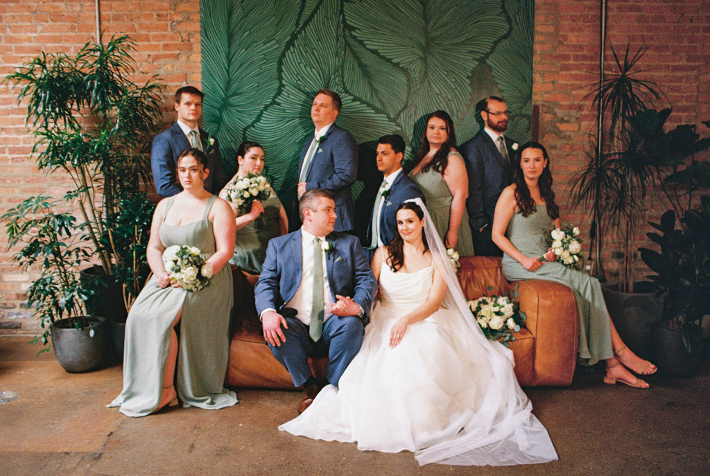 Film portrait of wedding party posing indoors on and around a couch at The Arbory, bride and groom seated at the center
