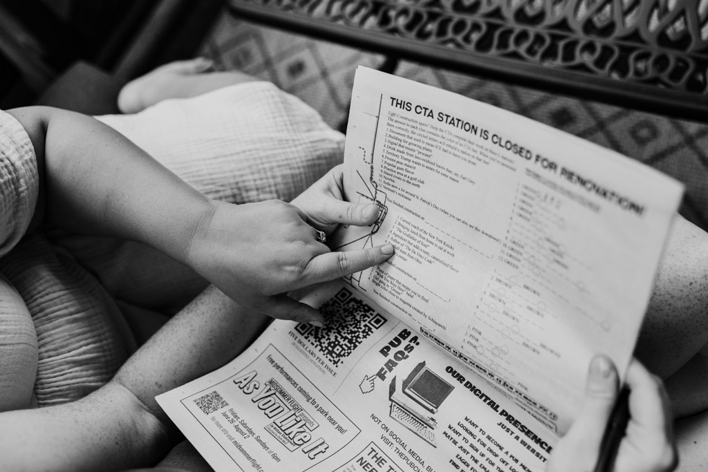 Black and white photo of engaged couple reading a newspaper on their balcony in Wicker Park