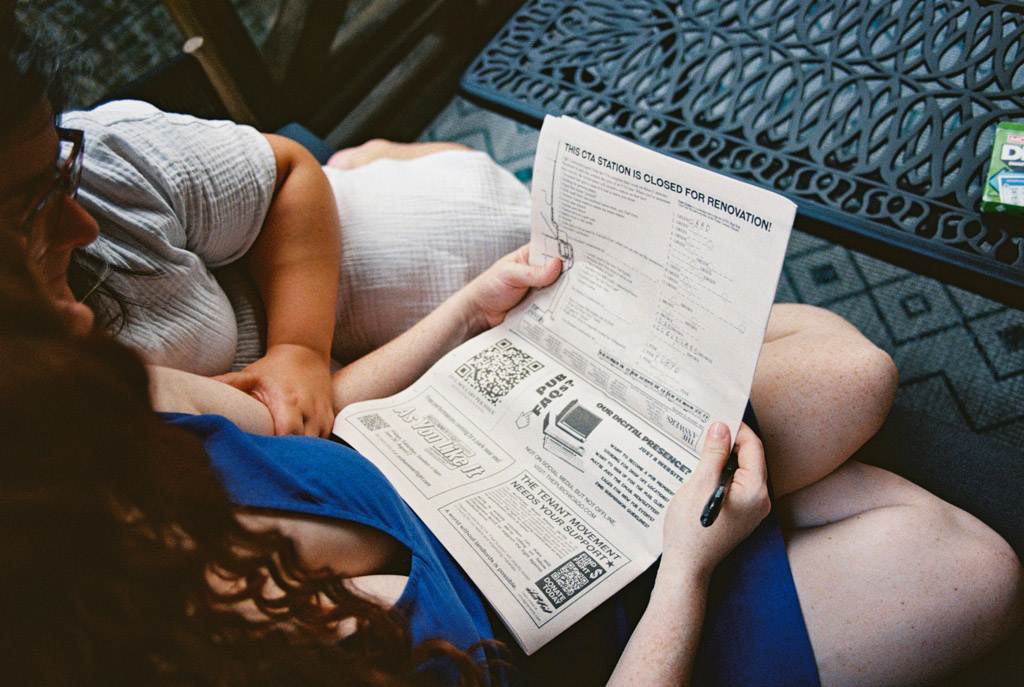 Engaged couple sits close together on their balcony, doing a crossword puzzle