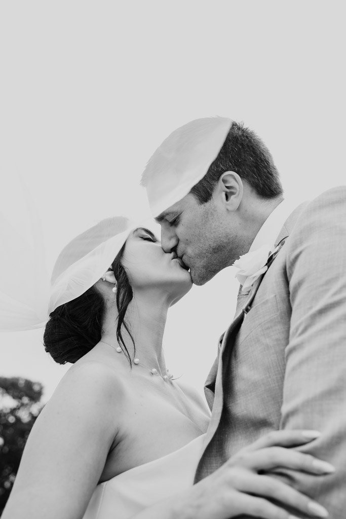 Black and white photo of bride and groom kissing outdoors after their Alfred Caldwell Lily Pool elopement