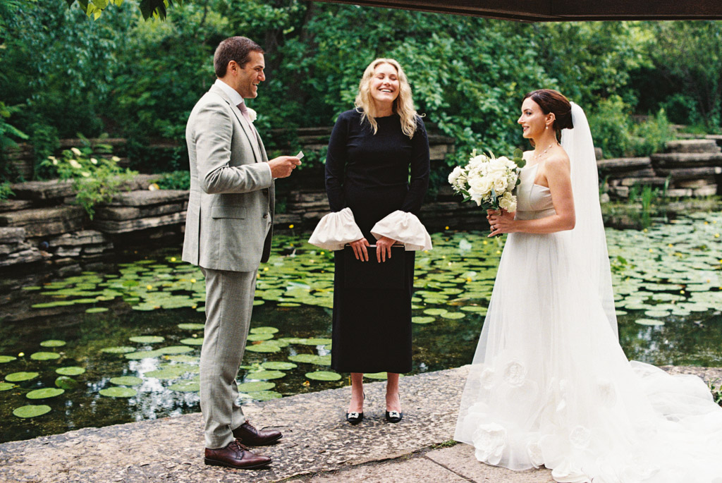 Film photo of groom reading his vows standing by bride and officiant during his intimate Alfred Caldwell Lily Pool elopement ceremony