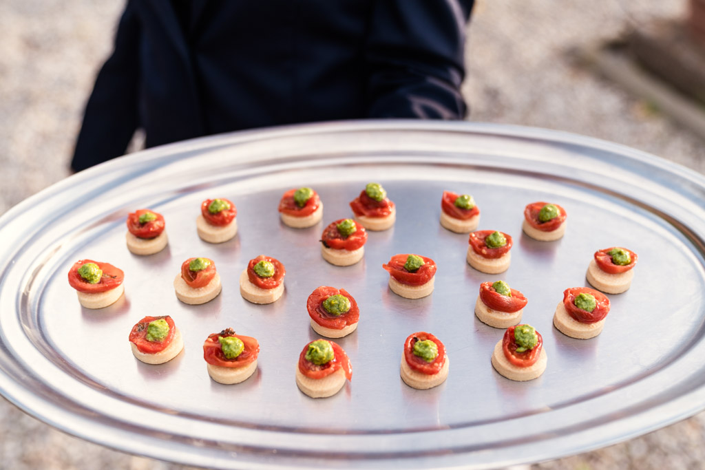 Silver tray with small, round appetizers topped with red sauce and green garnish for Italian Villa wedding reception