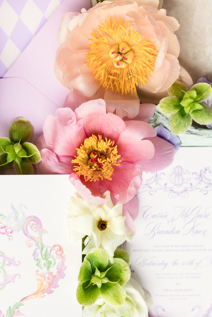 Pink, peach, and green flowers arranged with pastel stationary and envelopes featuring elegant calligraphy for Italian Villa wedding celebration