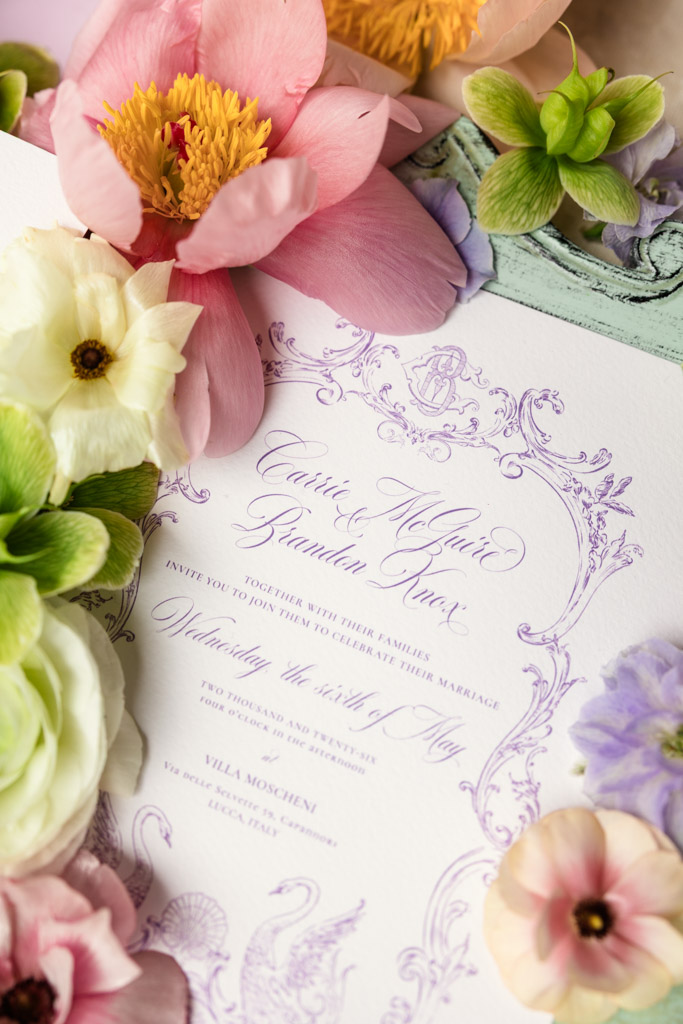 Wedding invitation with elegant purple script, surrounded by colorful pink, white, and green flowers—perfect for an enchanting Italian Villa wedding.