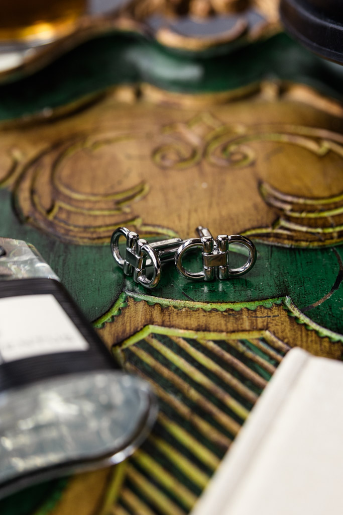 Silver cufflinks on a decorative green and gold surface for an Italian Villa wedding