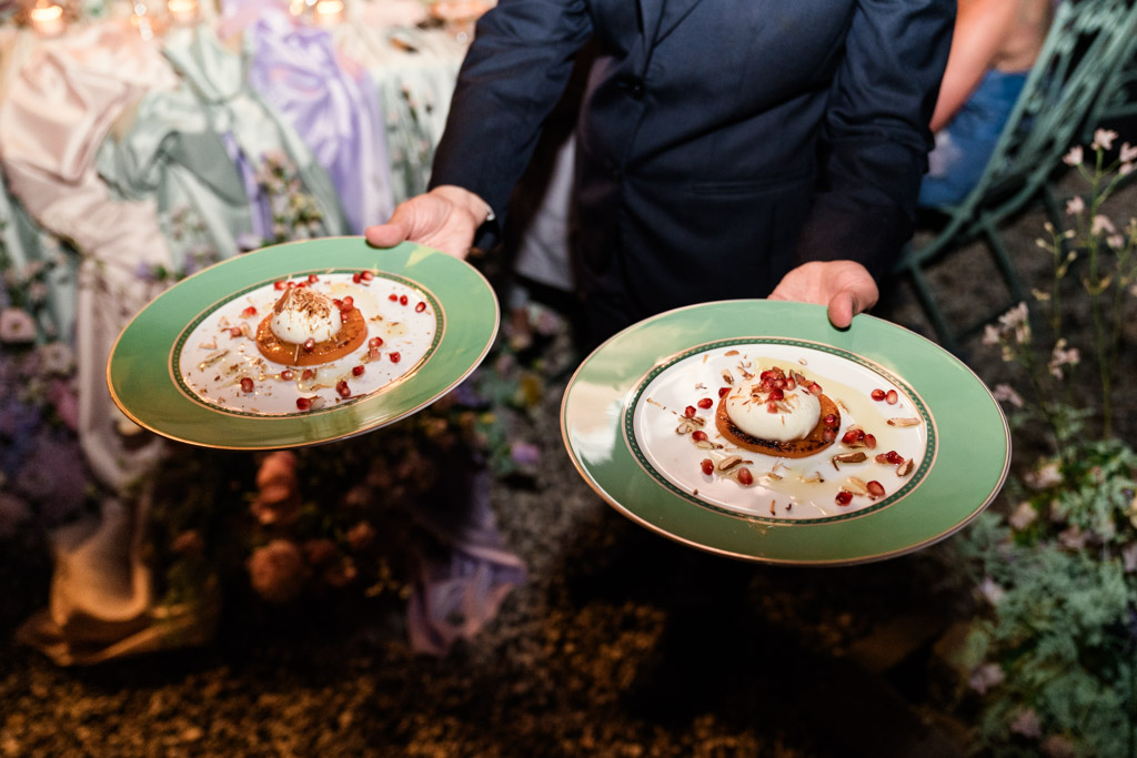 A server holds two green plates for Italian Villa wedding reception