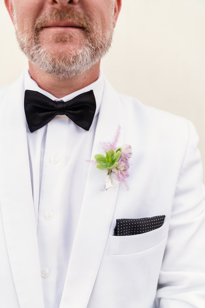 Groom in white suit jacket with black bow tie and boutonniere, showing only lower face and upper tors for his Italian Villa wedding
