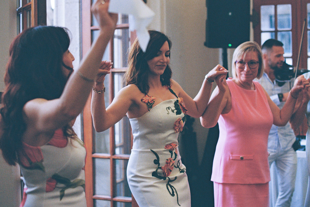 Film photo of bride and two guests holding hands and dancing indoors during wedding celebration at the University Club of Chicago