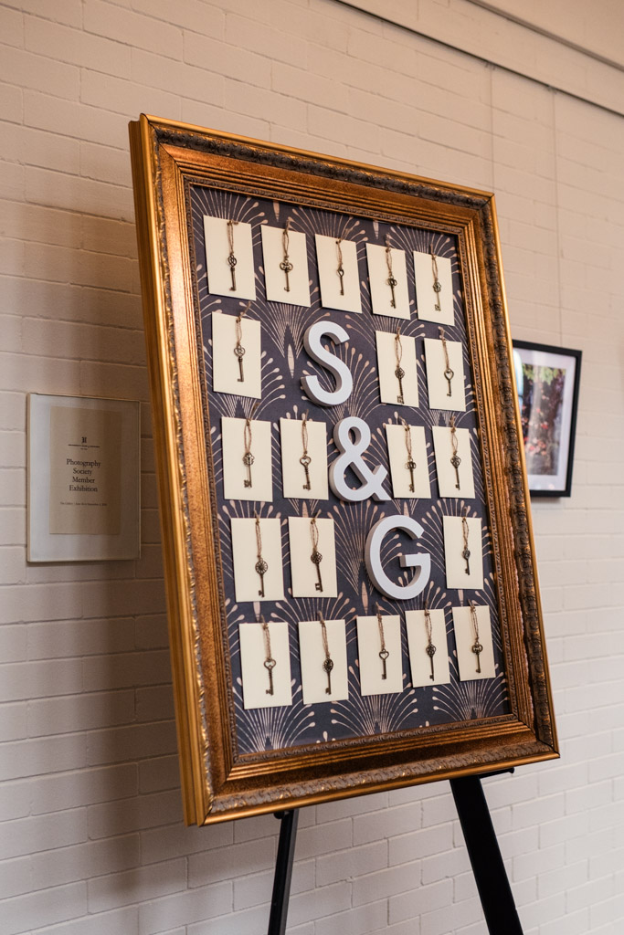 A gold-framed board with cards, vintage keys, and large “S & G” letters displayed on an easel for wedding celebration at the University Club of Chicago