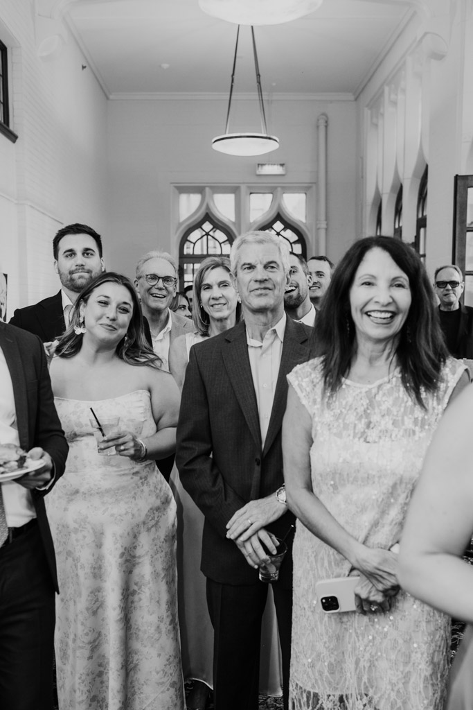 Black and white photo of guests dressed formally, smiling and gathered together for wedding celebration at the University Club of Chicago