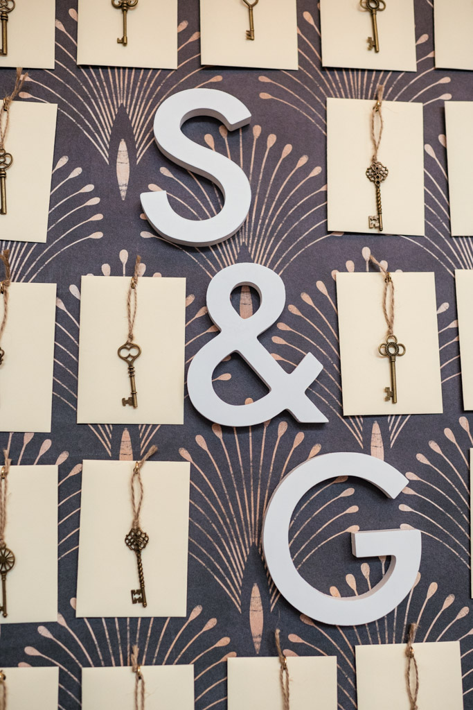 Large white “S & G” letters on a patterned wall with vintage keys and cards hanging on twine for wedding celebration at the University Club of Chicago