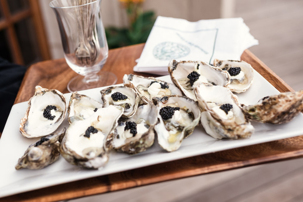 A platter of oysters topped with black caviar on a white tray for wedding celebration at the University Club of Chicago