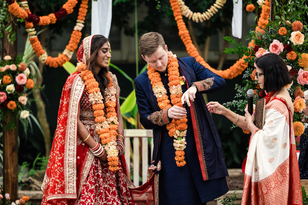 Bride and groom exchange garlands at a colorful Chicago Indian wedding ceremony adorned with vibrant flowers and elegant decorations.