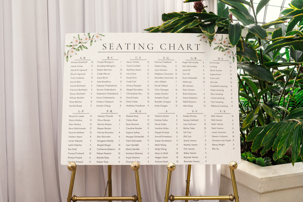 Wedding seating chart on easel with guest names listed alphabetically, surrounded by green plants for wedding reception at Garfield Park Conservatory