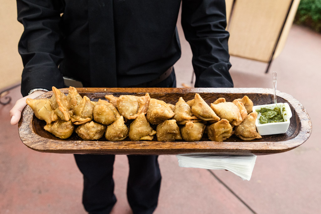 A wooden tray of samosas with green chutney , perfect for a Chicago Indian wedding celebration at Garfield Park Conservatory