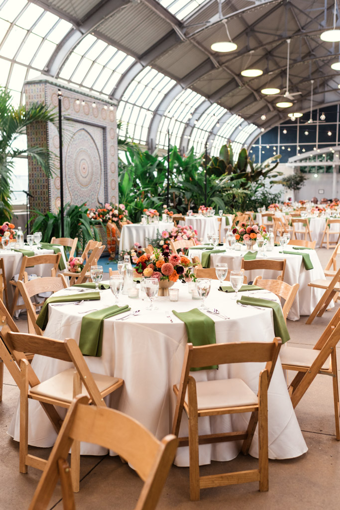 Round tables with white cloths, green napkins, and flower centerpieces for Chicago Indian wedding at Garfield Park Conservatory