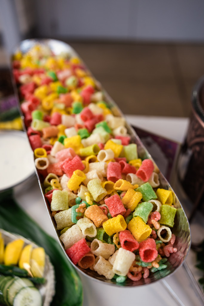 A tray filled with colorful, tube-shaped fried snacks, including red, yellow, green, and white pieces for wedding reception at Garfield Park Conservatory